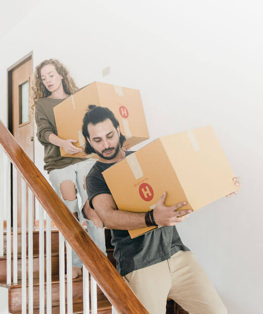 Couple carrying boxes down stairs